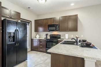 Kitchen with matching black appliances and caramel brown finishes at The Villas at Wilderness Ridge in South Lincoln, Nebraska